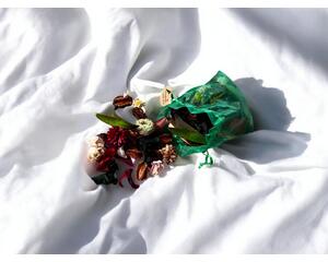 Nana's Apple Pie Sachet laid out on a white bed sheet with sun and shadows adding to the professional look of this image.